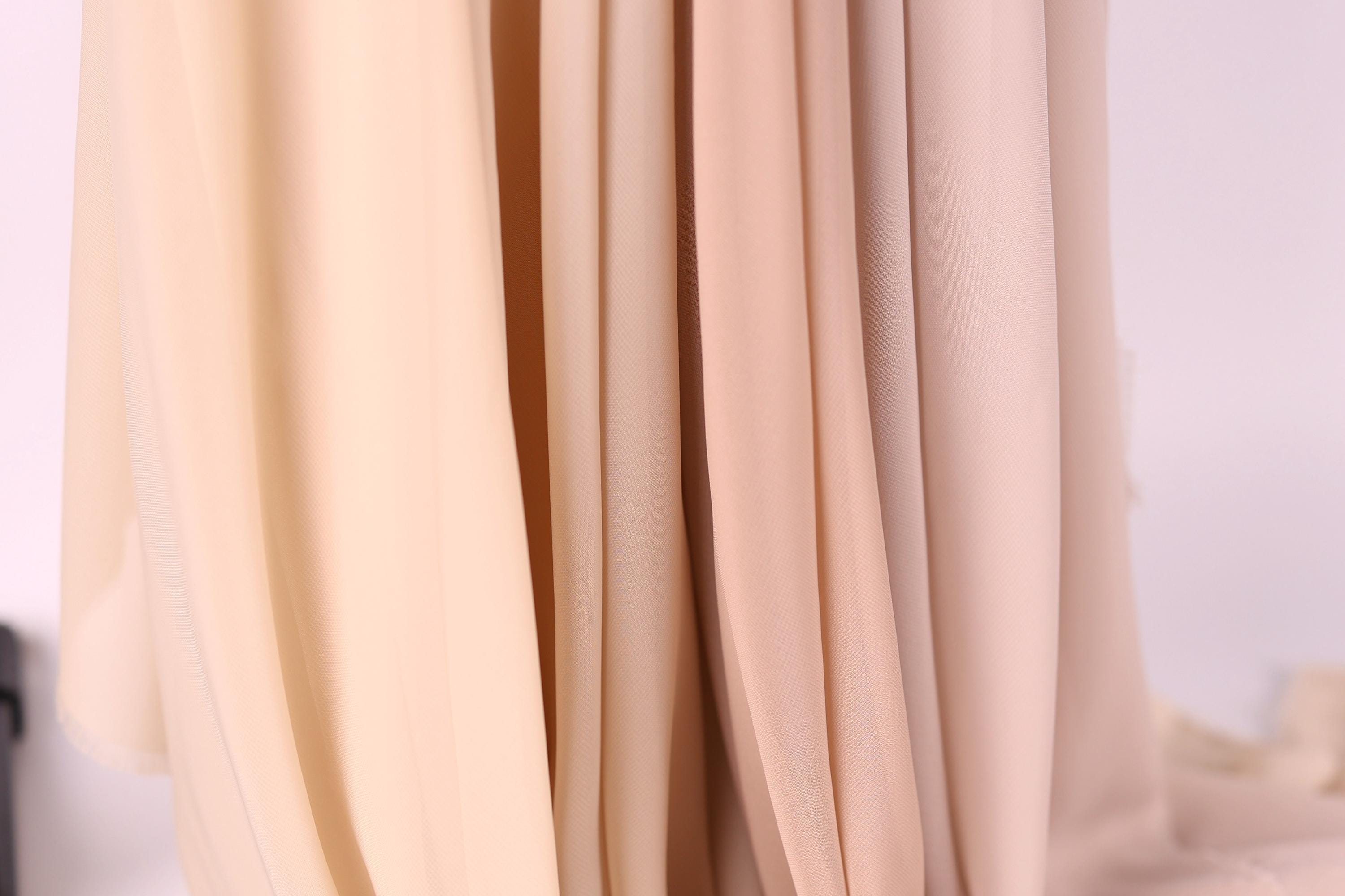 A close-up view of a fabric with a soft, light beige color.