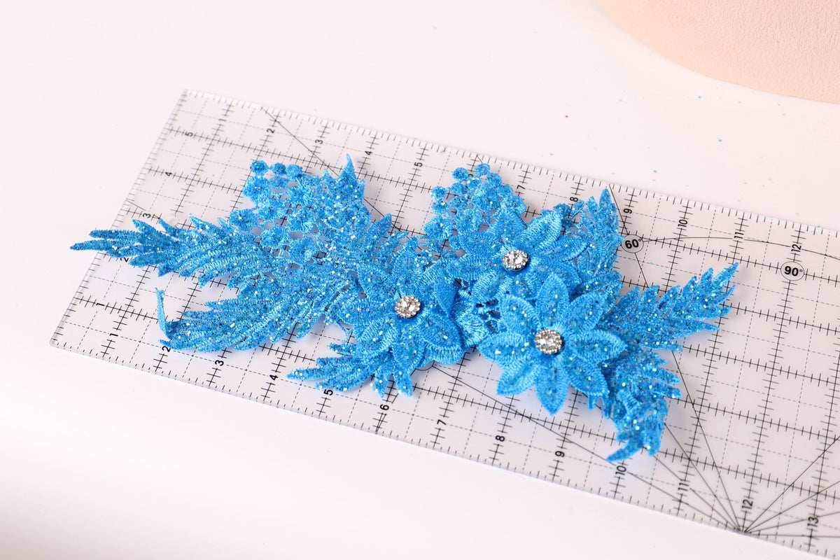a clear ruler with blue glittery flower-like decorations placed on it.