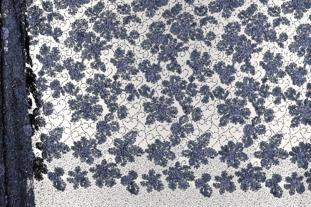 a close-up view of a fabric with a floral pattern. The fabric appears to be a blend of blue and white colors, with a repeating floral design that creates a visually appealing and intricate pattern.