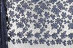 a close-up view of a fabric with a floral pattern. The fabric appears to be a blend of blue and white colors, with a repeating floral design that creates a visually appealing and intricate pattern.