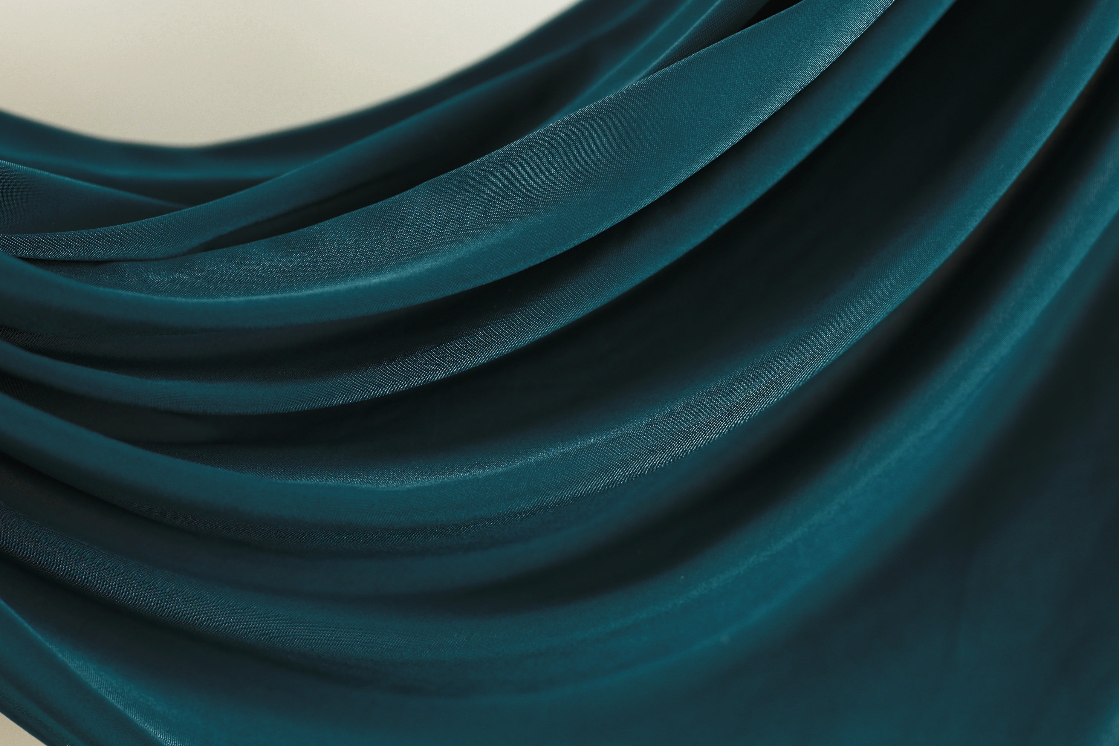 a close-up view of a dark blue fabric, possibly silk or chiffon, with a smooth, flowing texture. The fabric appears to be made of a shiny material, giving it a glossy and luxurious appearance.