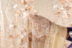 a close-up view of a delicate, beige and gold fabric adorned with intricate, sparkling embellishments.