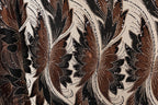 a close-up view of a fabric with a floral pattern in shades of brown and black, adorned with small white beads.