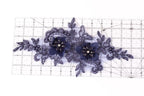 a decorative piece with blue lace and flowers, placed on a ruler for scale.