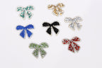 six small, colorful, and sparkling bow-shaped objects arranged on a white background.