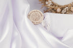 a close-up of a white fabric with a wooden circular logo placed on it, which appears to be a sewing artisan's shop.