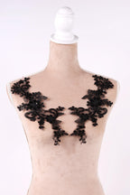 A mannequin wearing a beige dress with black lace appliques on the shoulders.