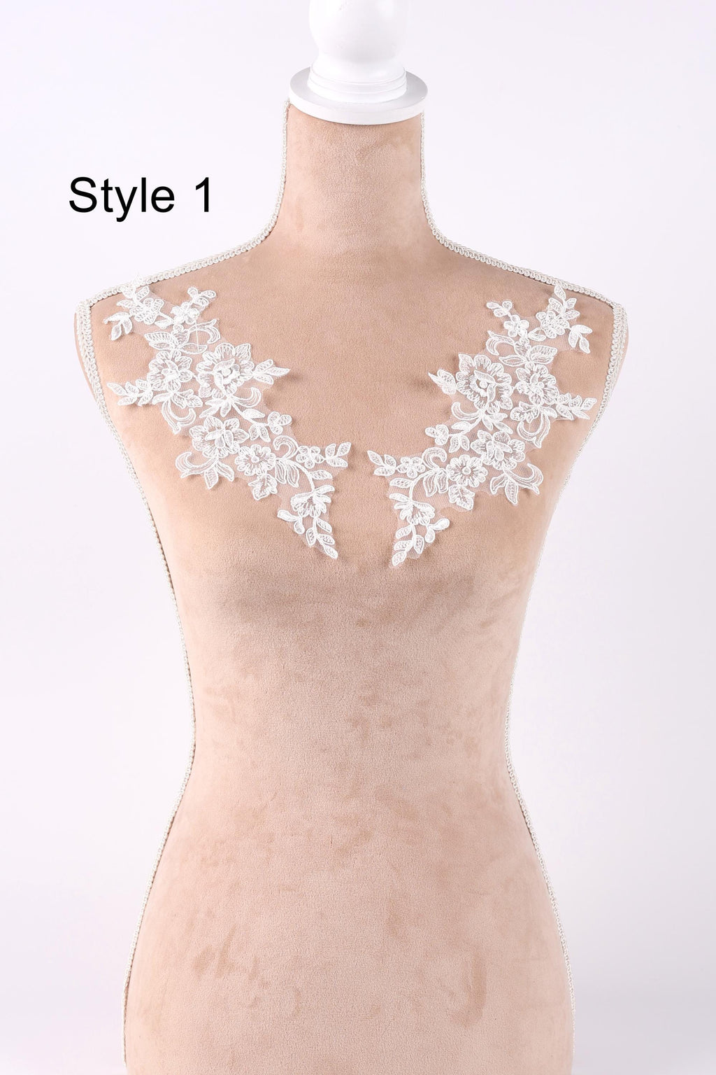 A mannequin with a beige body and white lace flowers on the shoulders, displayed against a white background.