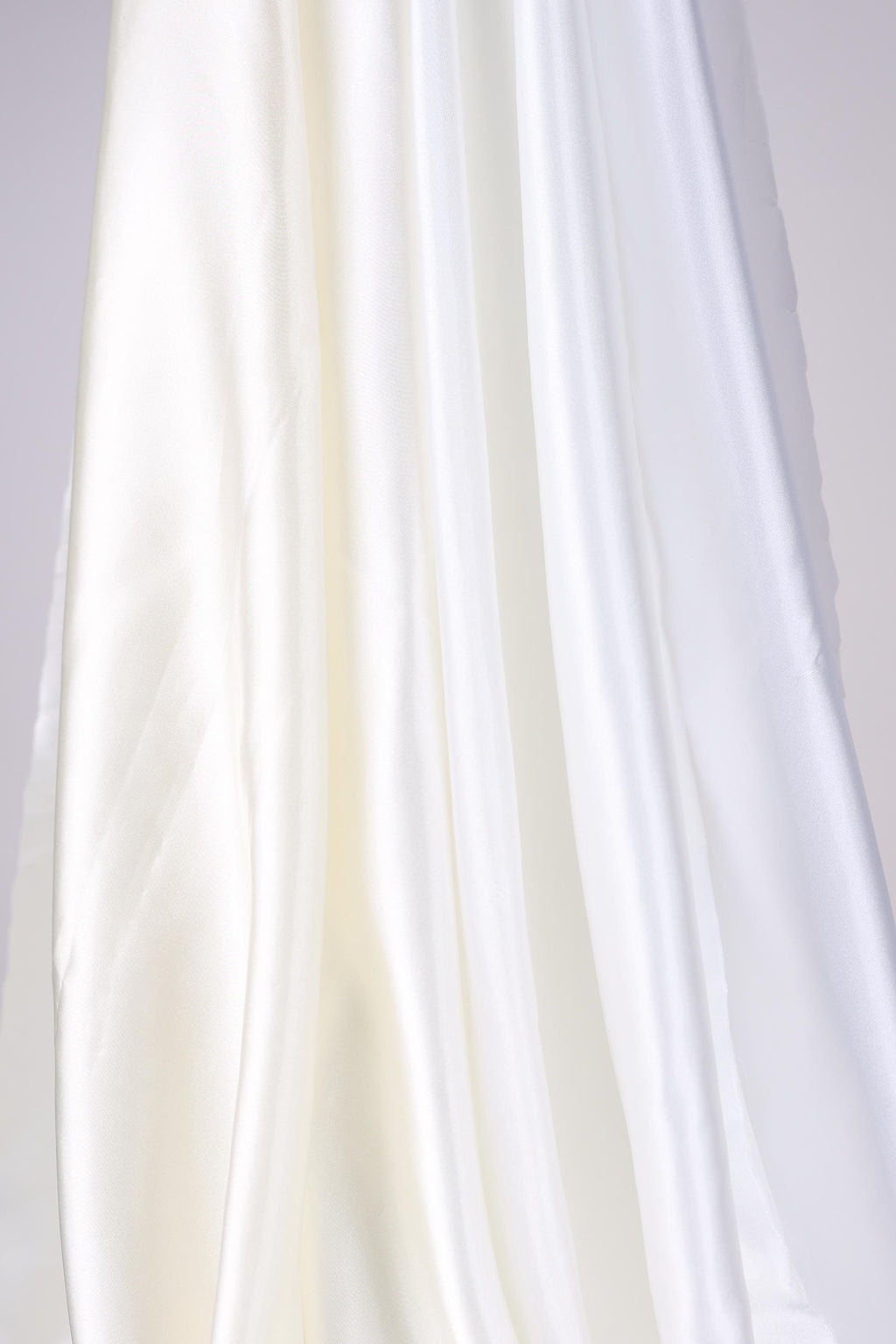The image is a close-up of a white fabric, possibly silk or chiffon, with a soft, flowing texture.