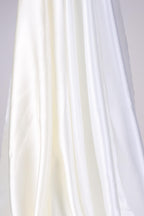 The image is a close-up of a white fabric, possibly silk or chiffon, with a soft, flowing texture.