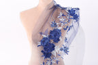A mannequin torso wearing a blue and white floral embroidered shawl or scarf.