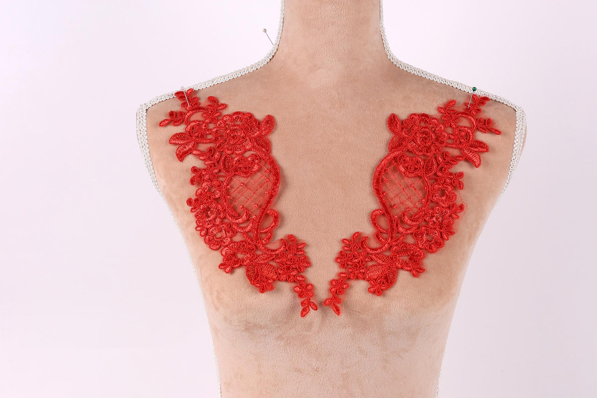 A mannequin with red lace or embroidery pieces on its shoulders.