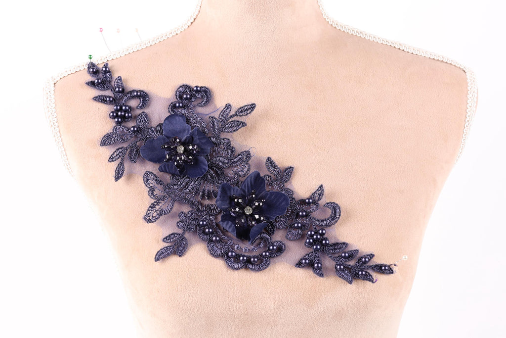 A mannequin torso with a decorative floral piece on it, featuring blue flowers and leaves with small pearls.