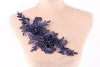 A mannequin torso with a decorative floral piece on it, featuring blue flowers and leaves with small pearls.