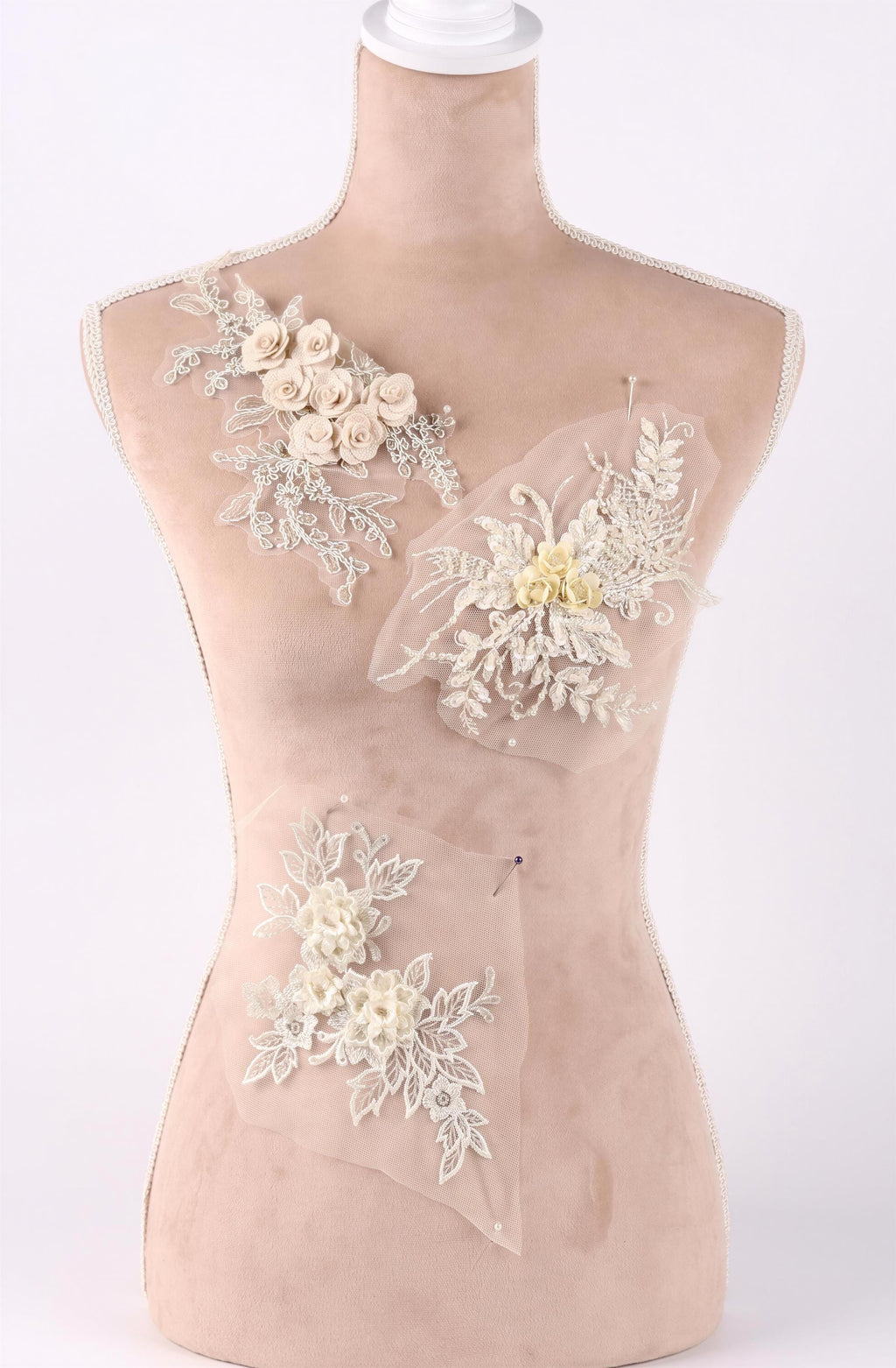 A mannequin with a beige body and white floral and lace embellishments on its chest area.