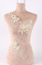 A mannequin with a beige body and white floral and lace embellishments on its chest area.
