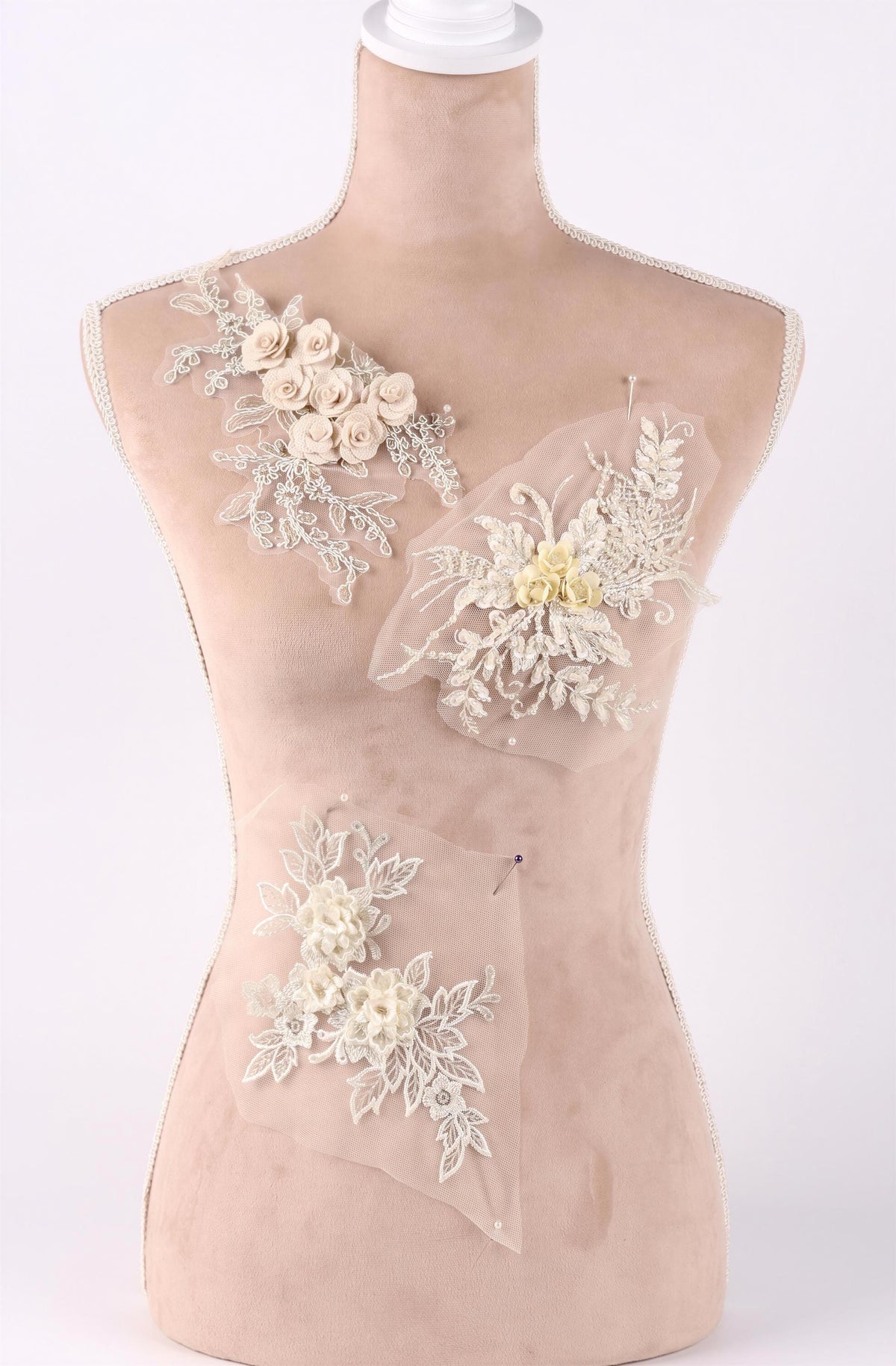 A mannequin with a beige body and white floral and lace embellishments on its chest area.
