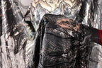A close-up view of a hand holding a piece of fabric with intricate black and silver sequin designs.