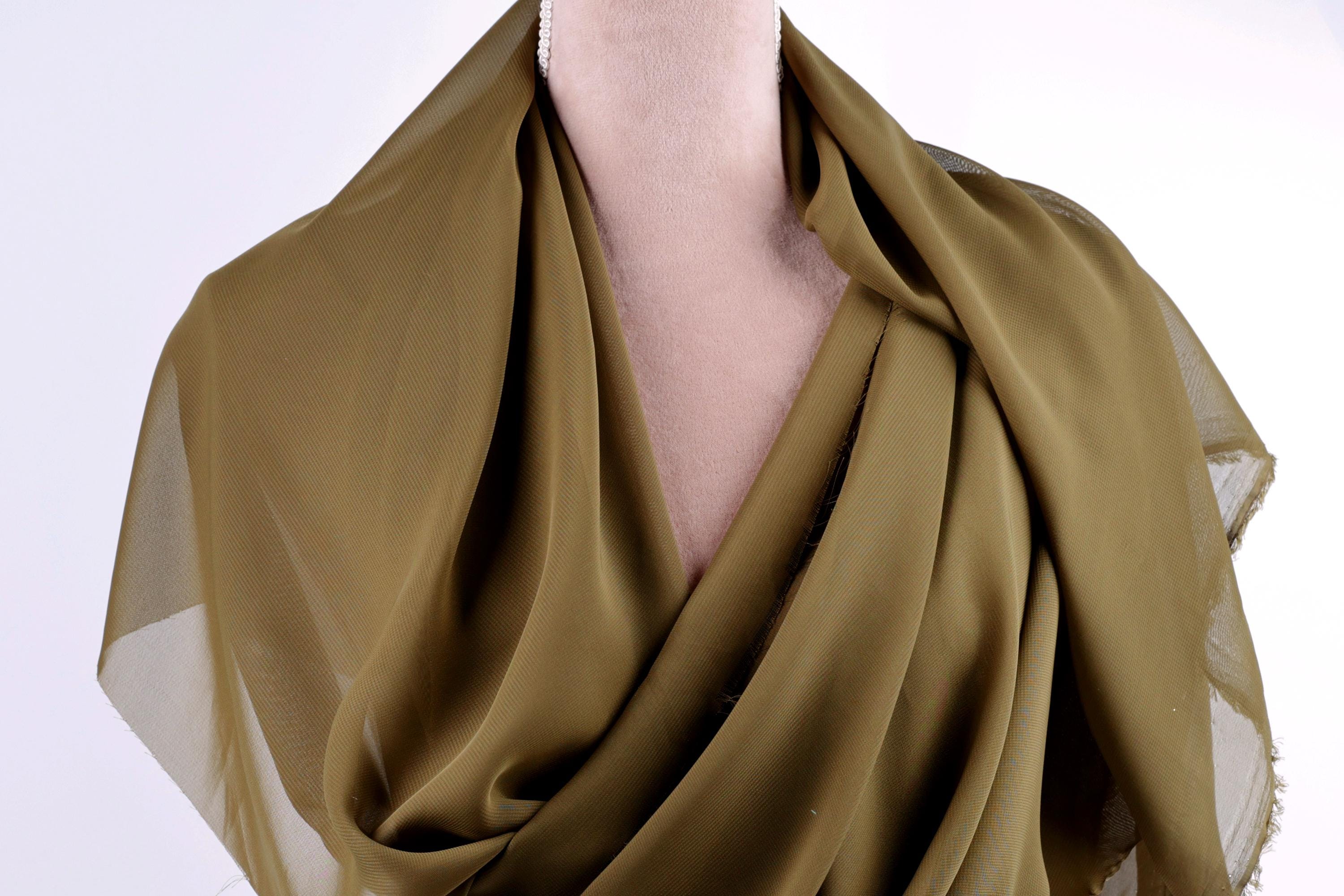 A close-up view of a mannequin wearing a green, draped fabric draped over its torso.
