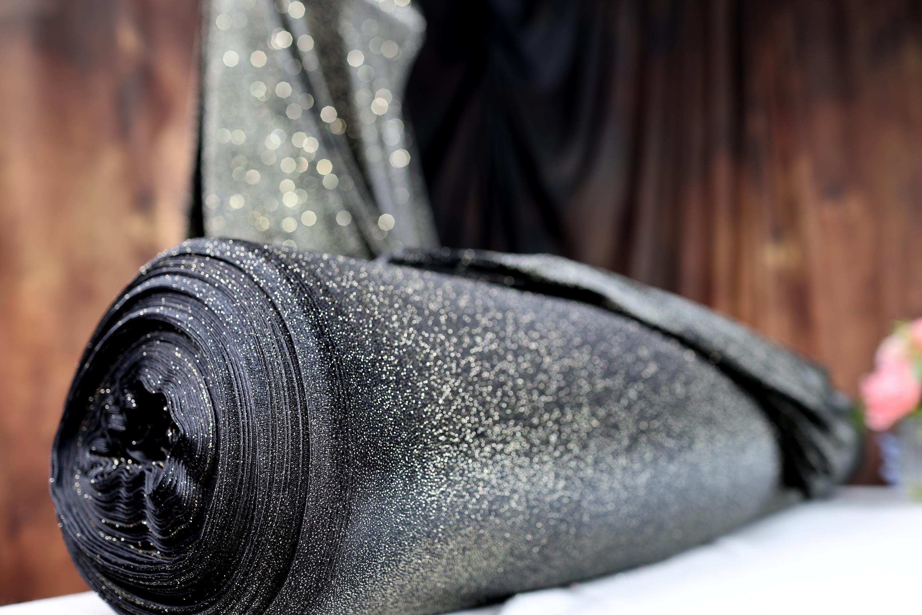 a roll of black fabric sitting on top of a bed