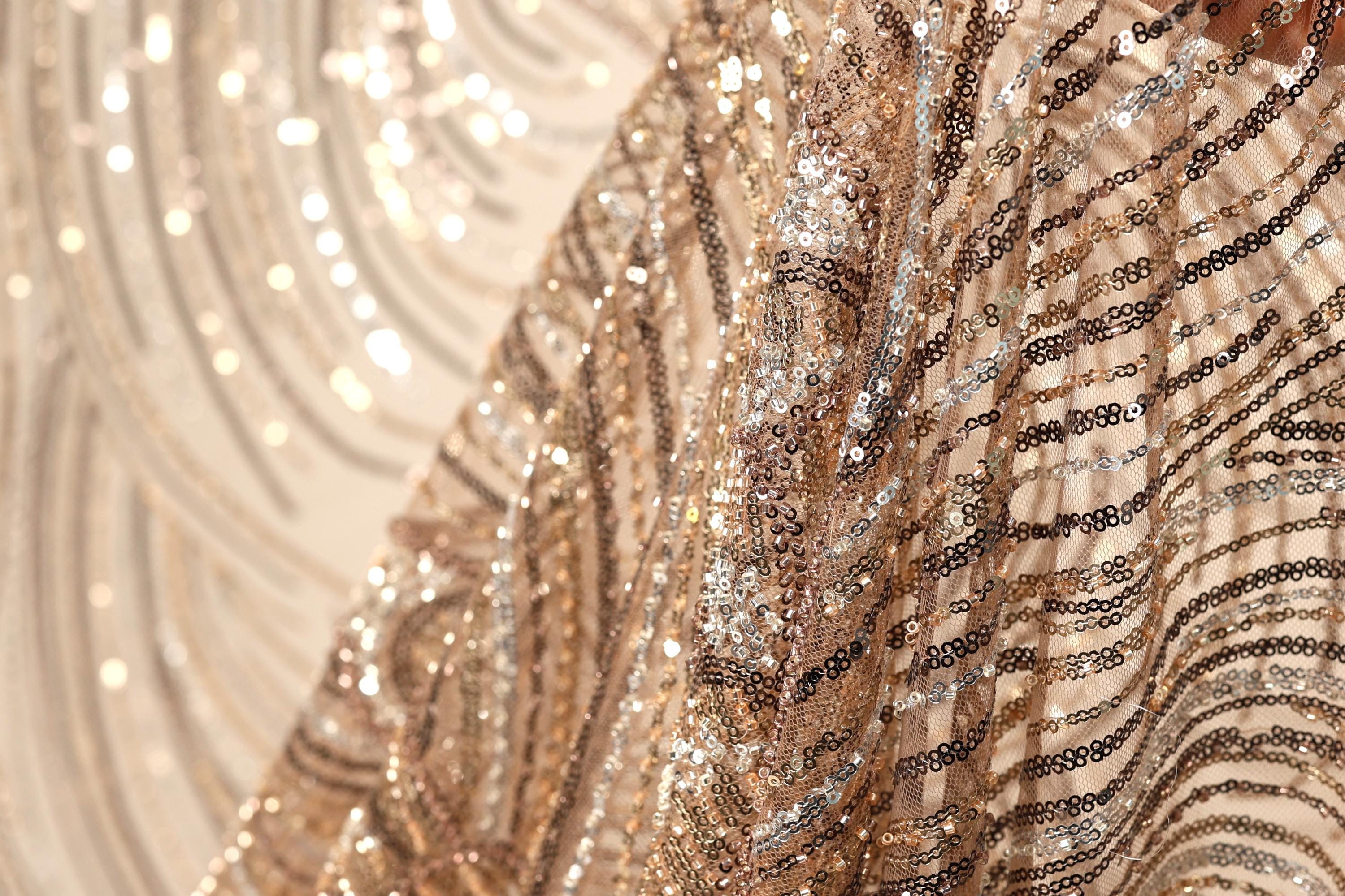 The image is a close-up of a sequined fabric, showcasing its intricate and shimmering patterns.