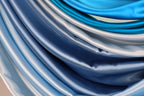 a close-up view of a collection of blue and silver fabric swatches, showcasing their smooth and shiny textures.