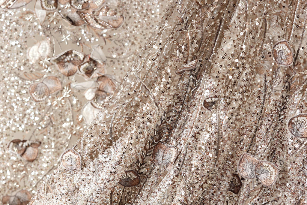 The image is a close-up of a fabric with a floral pattern, featuring a mix of brown and white colors.