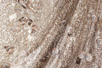 The image is a close-up of a fabric with a floral pattern, featuring a mix of brown and white colors.