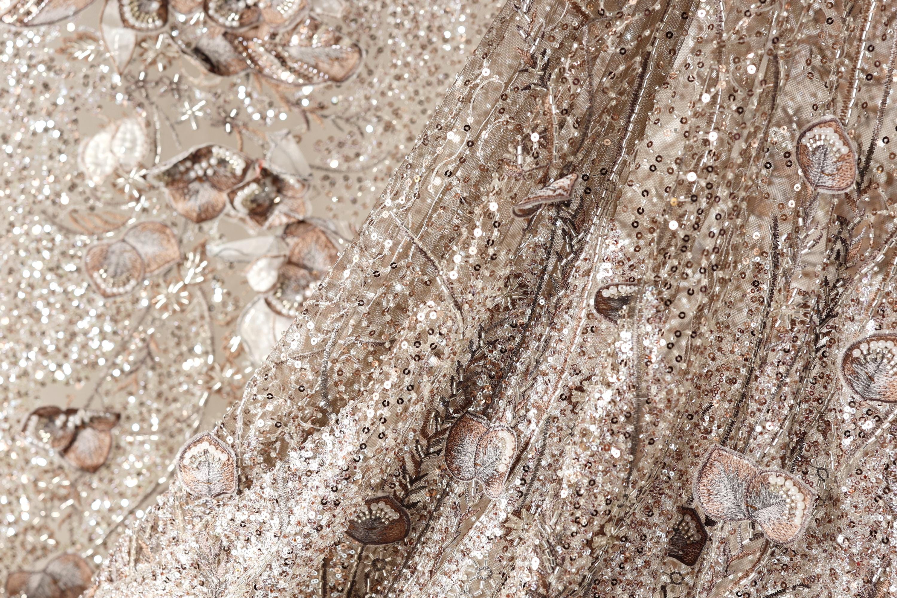 The image is a close-up of a fabric with a floral pattern, featuring a mix of brown and white colors.
