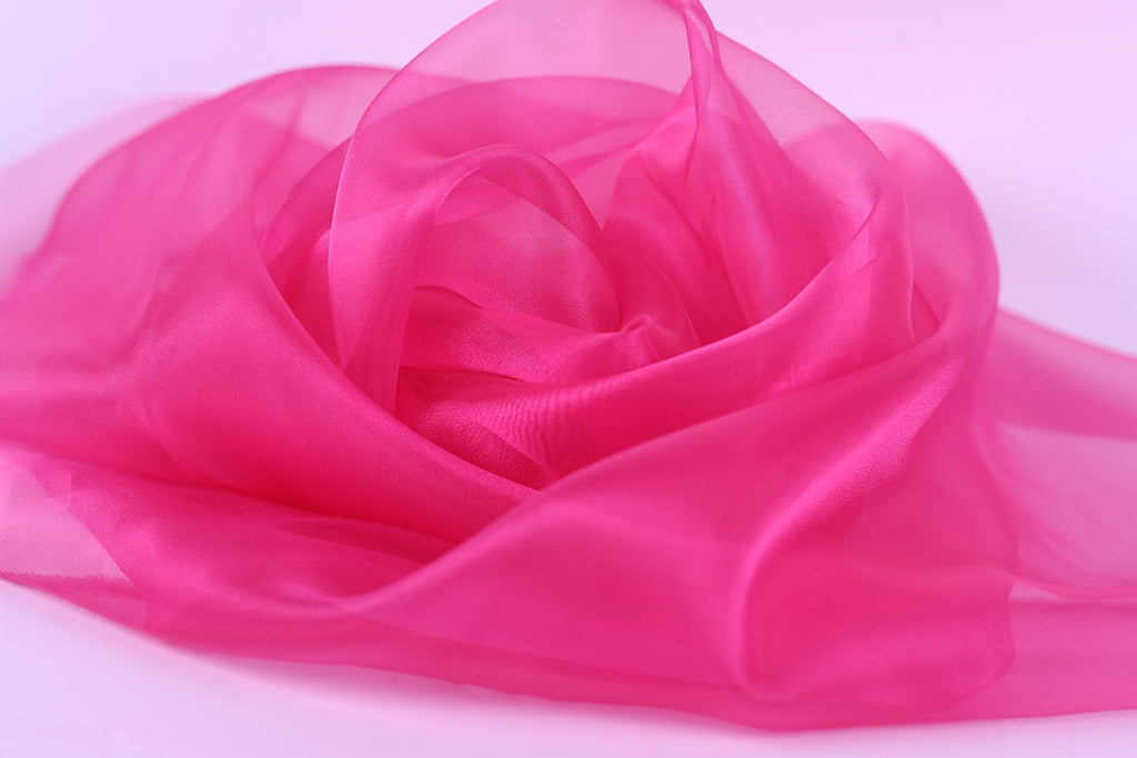 A close-up image of a soft, flowing pink fabric, resembling a delicate flower petal or a soft, silky fabric.