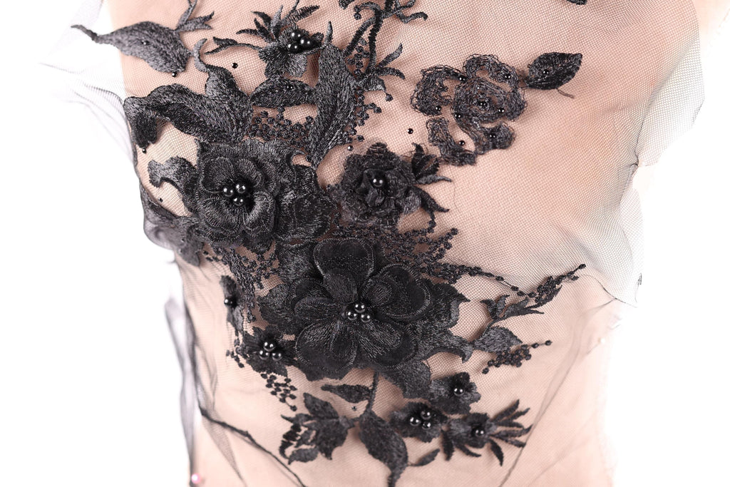a close-up view of a delicate black lace flower design on a fabric surface.
