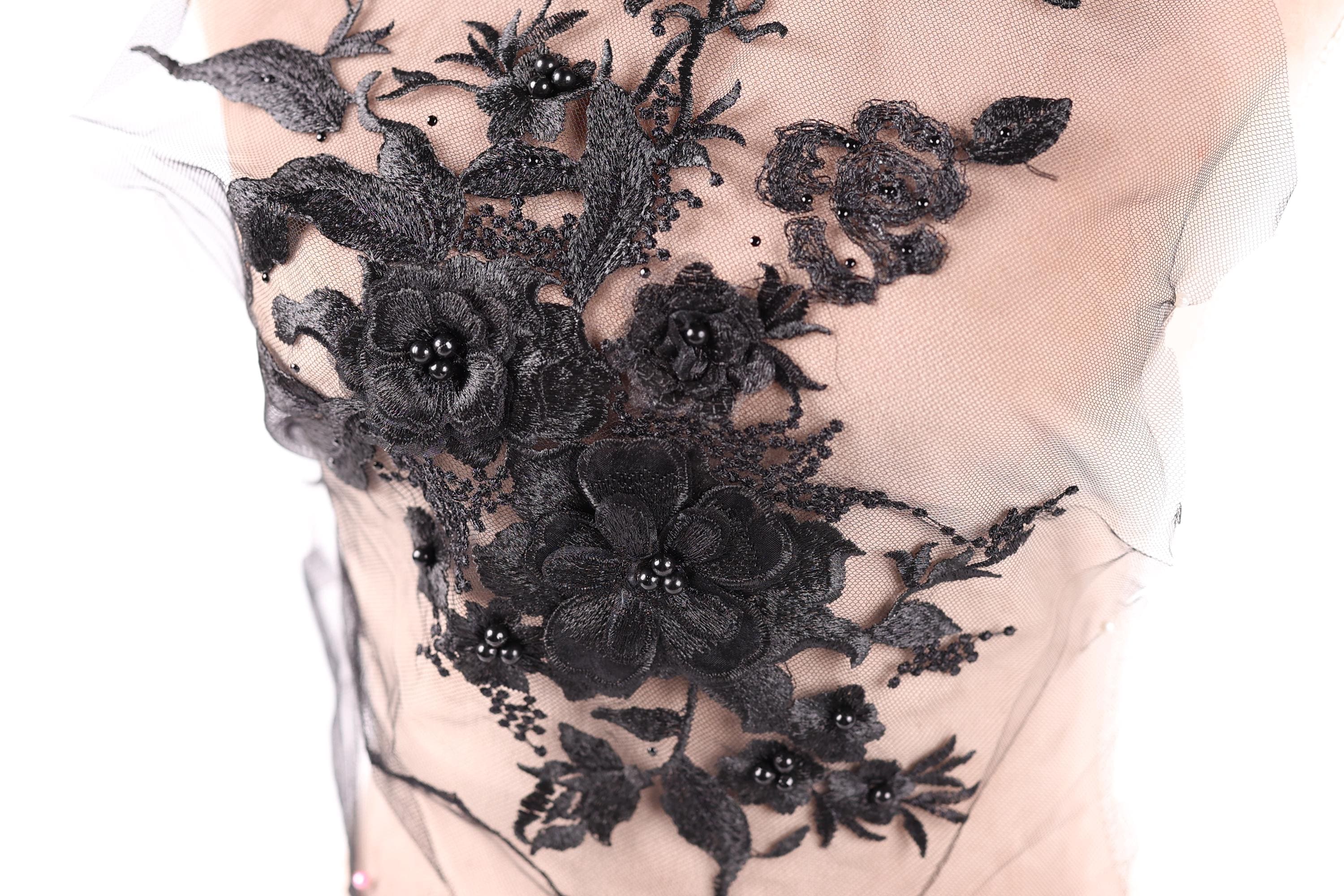 a close-up view of a delicate black lace flower design on a fabric surface.