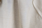 A close-up view of a fabric with horizontal stripes in various shades of white and beige.