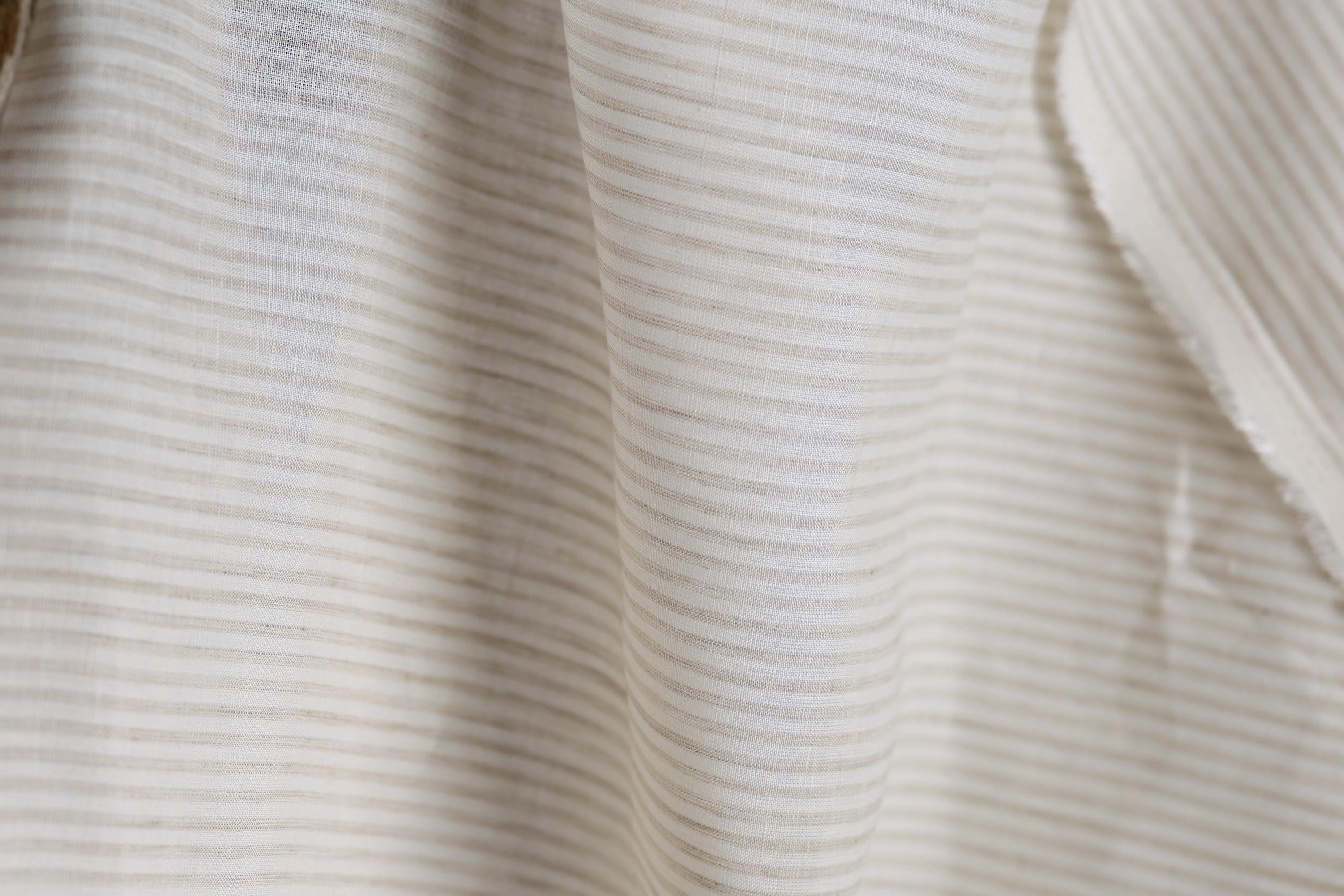 A close-up view of a fabric with horizontal stripes in various shades of white and beige.