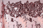 The image is a close-up of a fabric with a pink and red sequin pattern. The fabric appears to be a sheer material, with a textured and layered appearance. The pattern consists of various shades of pink and red sequins, creating a visually striking and intricate design.