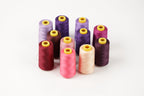A collection of colorful spools of thread in various shades of purple, pink, and maroon, arranged in a circular pattern on a white background.