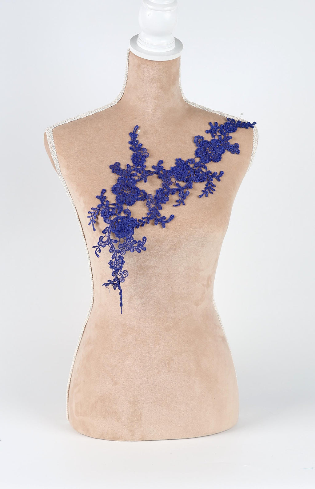 A mannequin with a beige body and a blue floral lace overlay on its chest.