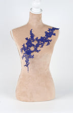 A mannequin with a beige body and a blue floral lace overlay on its chest.