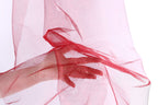A hand is holding a red, shiny fabric or material, which appears to be a sheer or sheer-like fabric. The hand is positioned in front of the fabric, with the fingers curled around it.