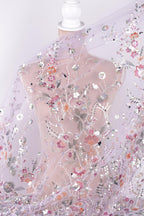 a mannequin wearing a sheer, floral-patterned fabric draped over it. The fabric has a delicate, transparent appearance and is adorned with a variety of colorful flowers and leaves. The mannequin is positioned in a way that allows the fabric to be fully visible, showcasing the intricate details and patterns of the fabric.
