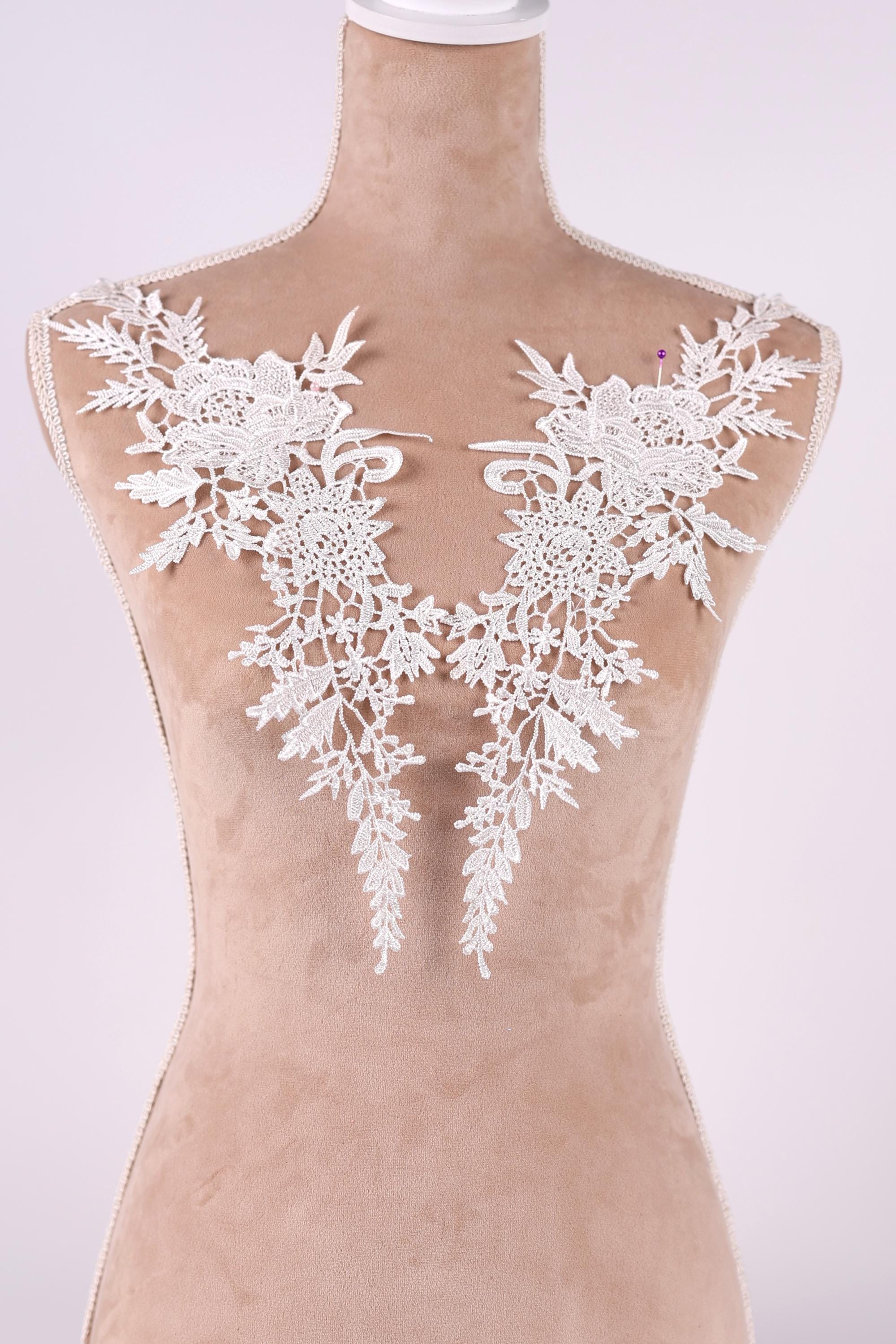 A mannequin wearing a dress with delicate white lace appliques on the shoulders.