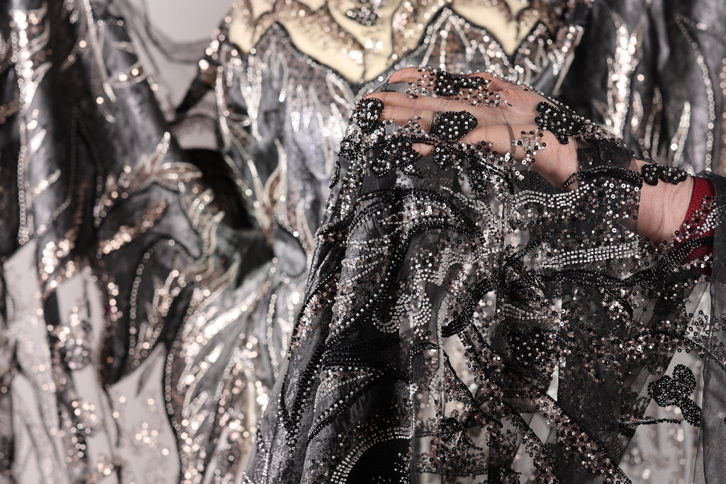 A close-up view of a black and silver sequined fabric, with intricate patterns and designs.