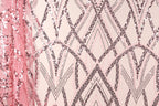 a close-up view of a fabric with a pink and black sequin pattern. The fabric appears to be a sheer material, with the pink sequins creating a visually striking contrast against the light-colored background. The pattern consists of various shapes and lines, including triangles, diamonds, and arches, which contribute to the overall design and texture of the fabric.