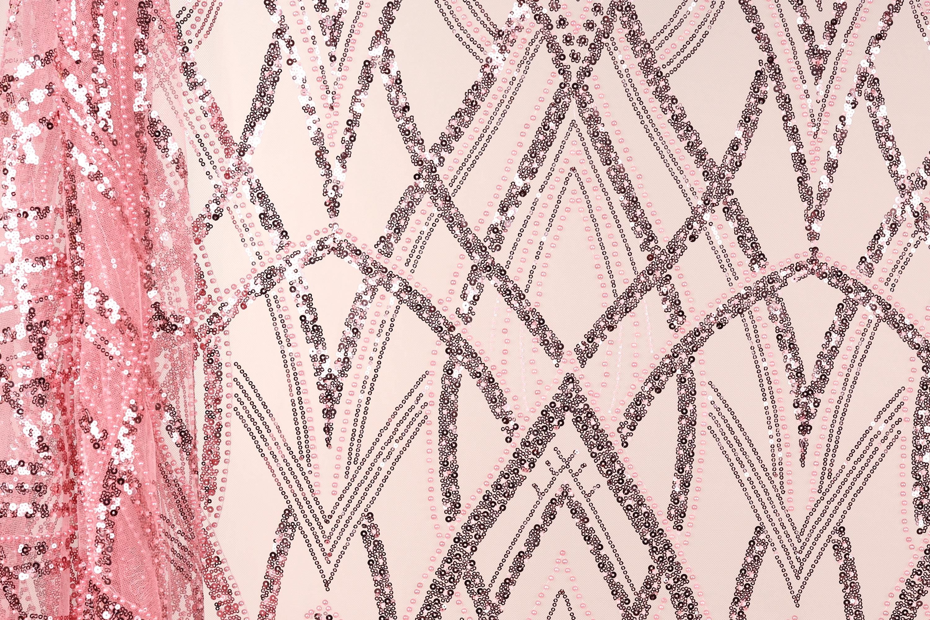 a close-up view of a fabric with a pink and black sequin pattern. The fabric appears to be a sheer material, with the pink sequins creating a visually striking contrast against the light-colored background. The pattern consists of various shapes and lines, including triangles, diamonds, and arches, which contribute to the overall design and texture of the fabric.