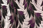 a close-up view of a fabric with a repeating pattern of purple and black leaves, accented with gold sequins. The pattern is intricate and detailed, creating a visually striking and textured appearance.