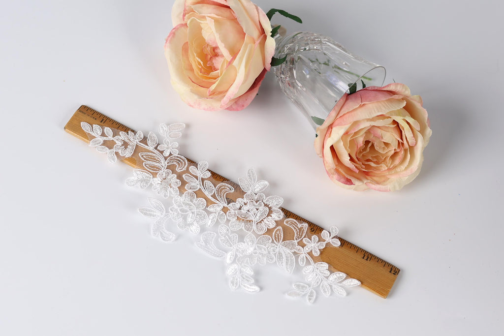 a lace piece, a wooden ruler, and two pink roses on a white background.