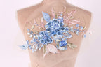 A mannequin with a delicate floral embroidered on its back, featuring blue and pink flowers and leaves.