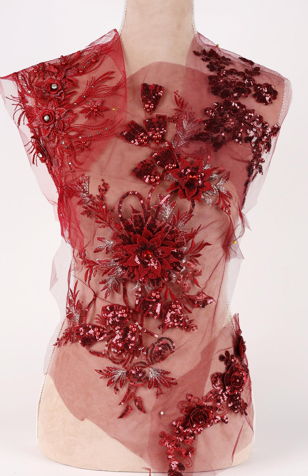 A mannequin wearing a red dress with intricate floral and sequin designs.