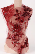 A mannequin wearing a red dress with intricate floral and sequin designs.