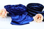 a close-up view of two fabric swatches, one blue and one black, with a single pink rose resting on the left side.